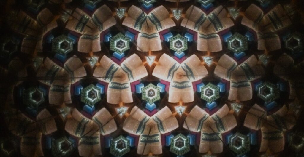 Kaleidoskooppikuva, jossa voi hahmottua kirjan selkämys, joka kertautuu aina uudelleen ja uudelleen pyörivässä liikkeessä.